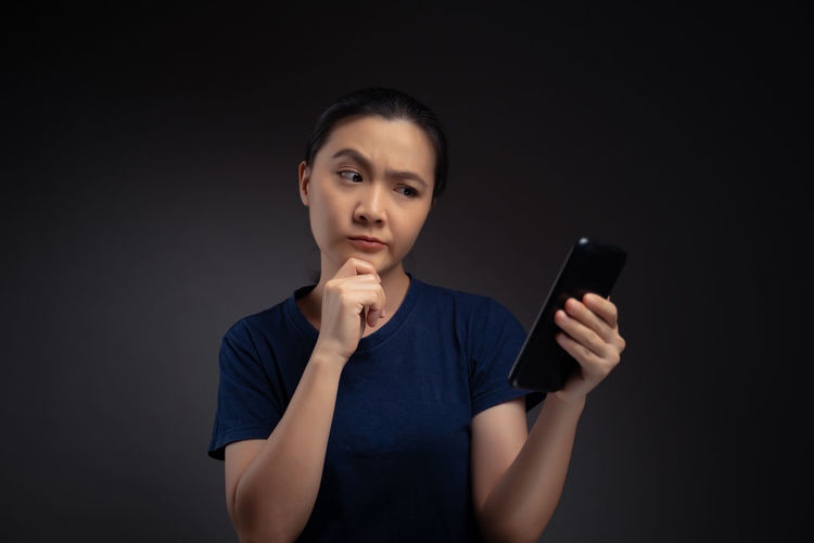 Young woman using smart phone against black background