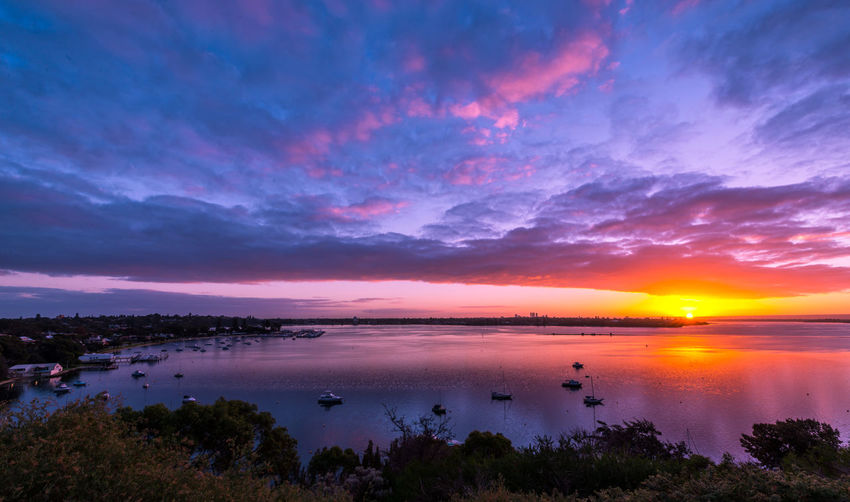 Scenic view of sea against dramatic sky during sunset
