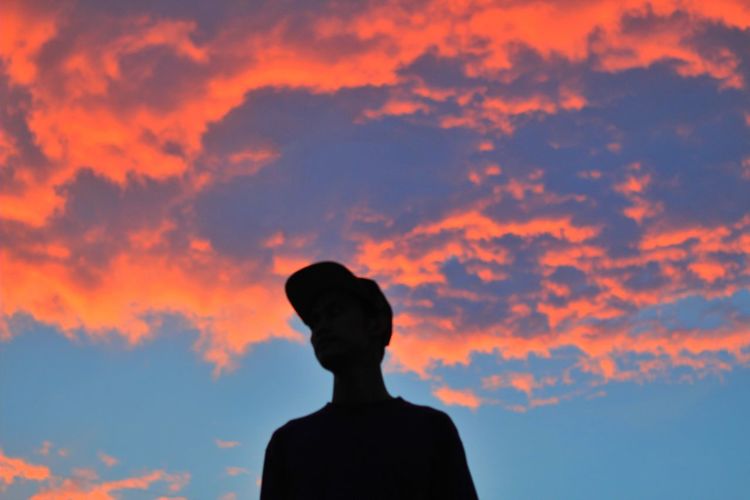 Rear view of silhouette man standing against orange sky
