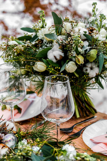 High angle view of wineglasses by flower arrangement on table 