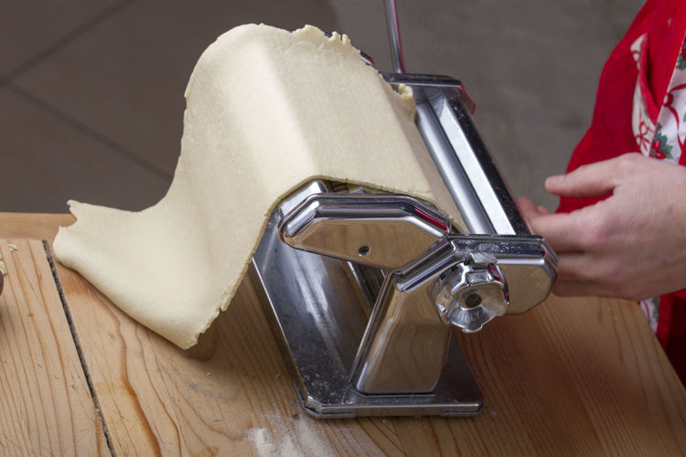 Midsection of woman preparing pasta through machine