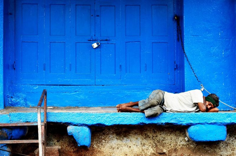 Poor man sleeping against closed shop