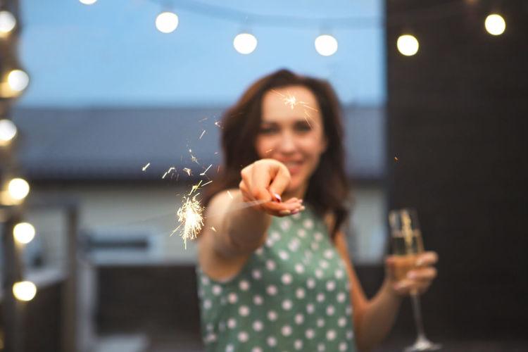 Portrait of smiling woman holding sparkler