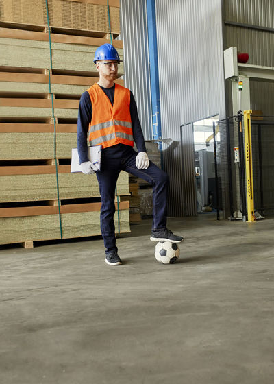 Worker standing in factory warehouse with football