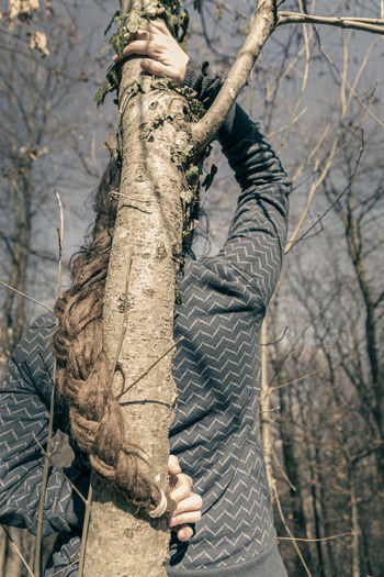 Man holding tree trunk in forest