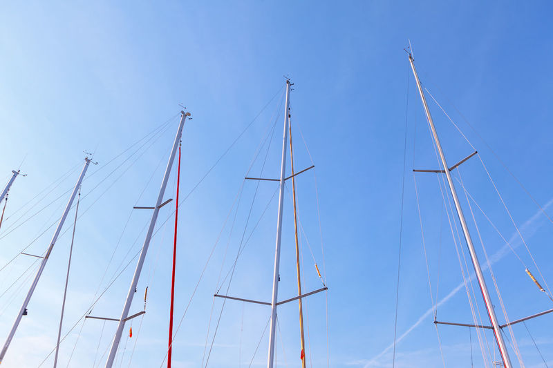Yacht masts without sails against blue sky
