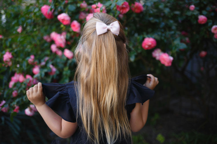 Rear view of girl looking at flowers outdoors