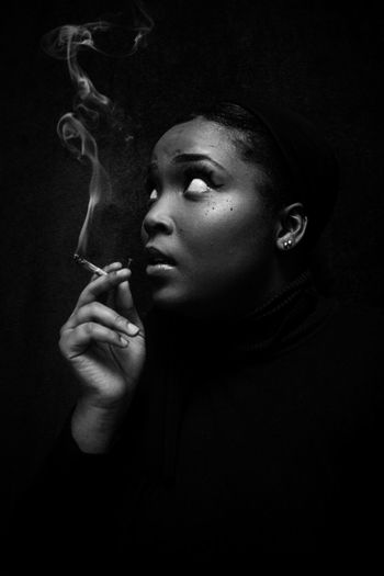 Portrait of man smoking cigarette against black background