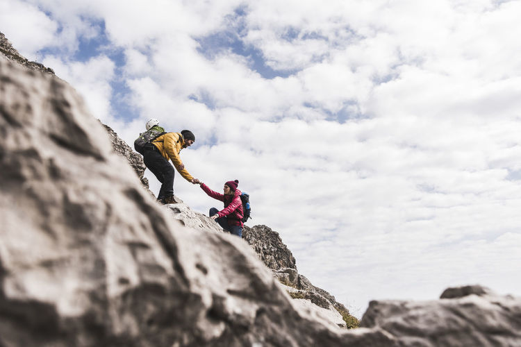 Germany, bavaria, oberstdorf, man helping woman climbing up rock