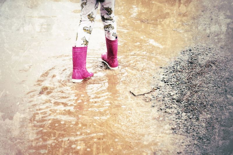 Low section of girl wading in puddle