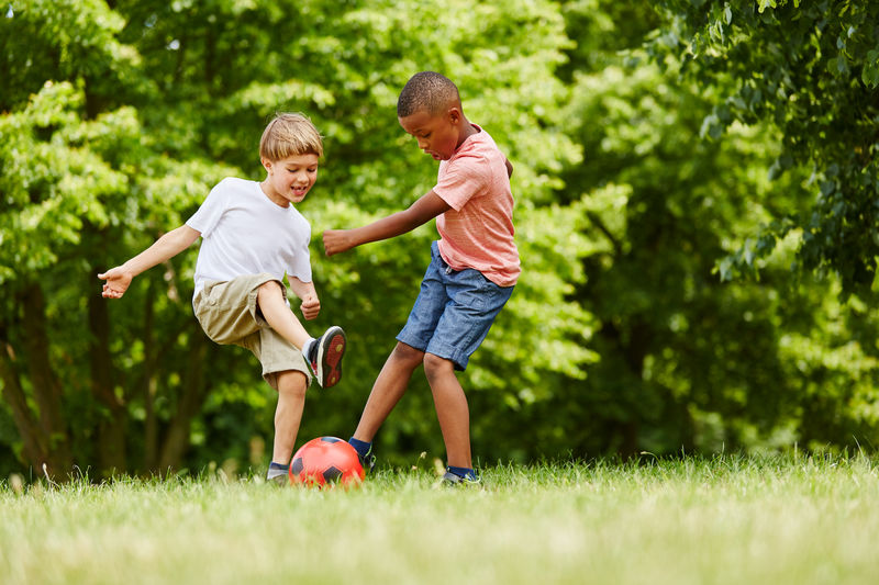 Full length of boys playing with soccer ball on grass