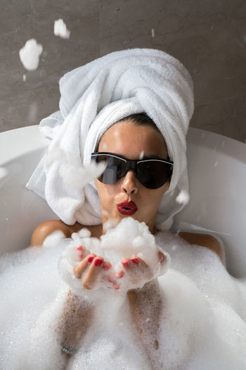 Woman blowing foam in the bathtub