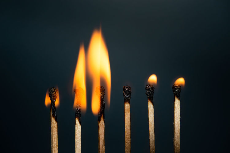 Close-up of burning candles against black background