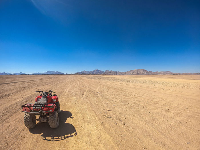 Tractor in desert against clear blue sky
