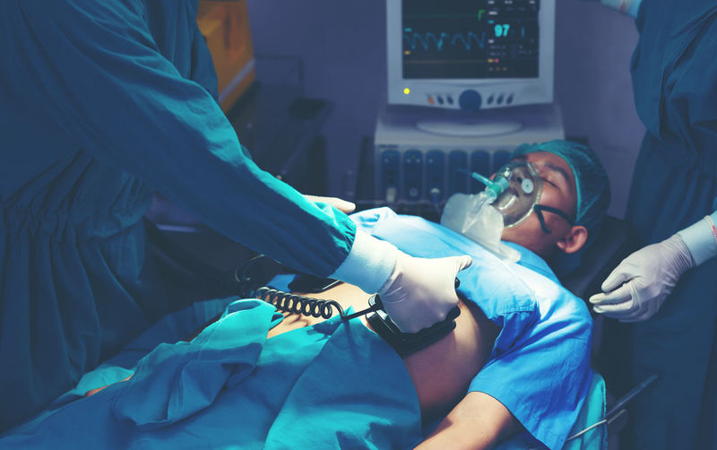 While performing medical surgery inside the operating room, a doctor and nurse use a defibrillator.