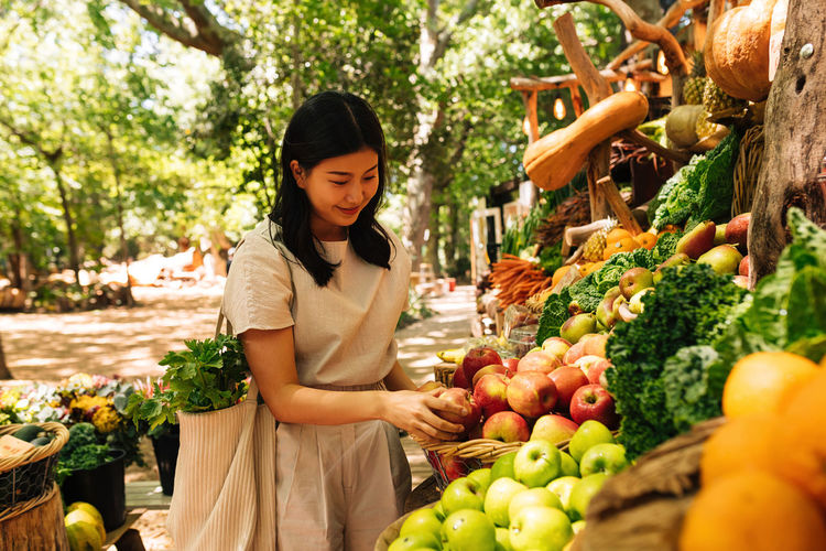 Portrait of young woman holding fruits at market