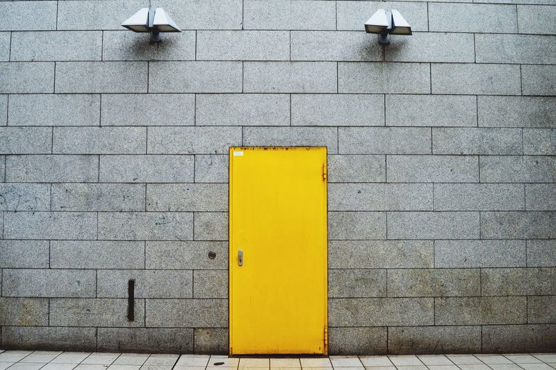 Closed yellow door of building with electric lights