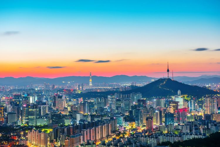 Illuminated cityscape against sky during sunset
