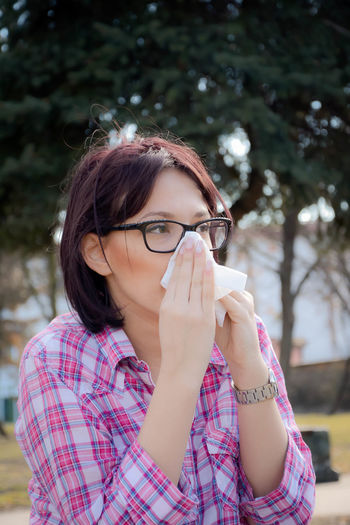 Portrait of young woman blowing nose