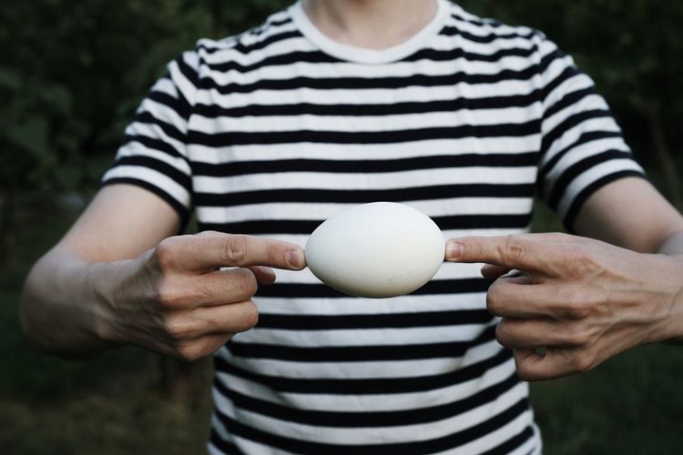 Midsection of man holding egg