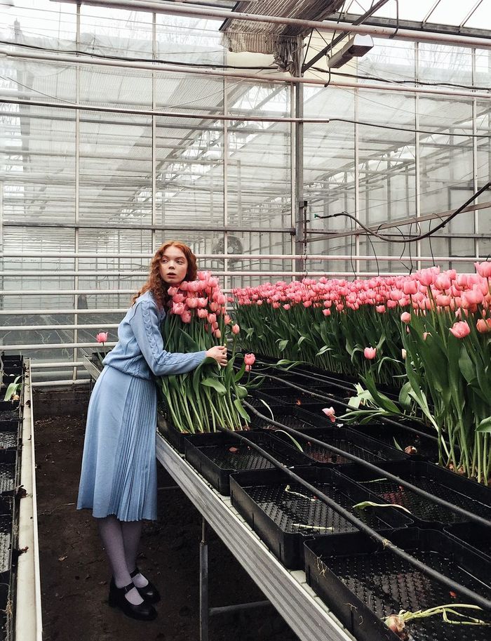 WOMAN STANDING IN A GREENHOUSE