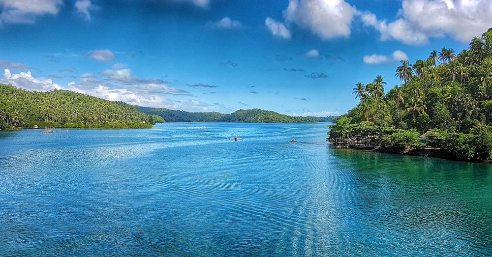 Swimming pool by lake against blue sky