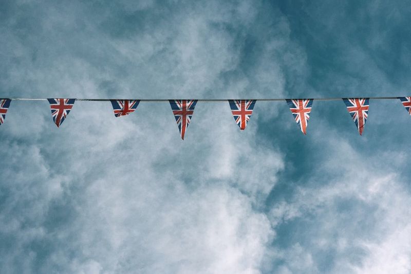 Low angle view of british flags bunting against cloudy sky