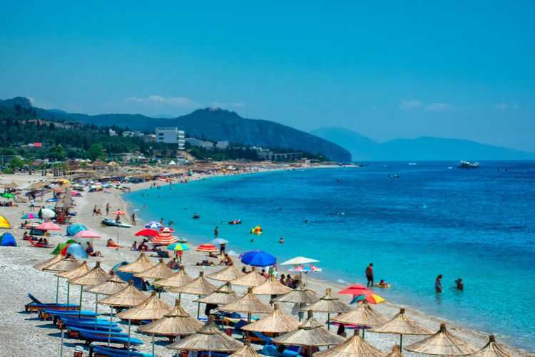 Panoramic view of people on beach against blue sky