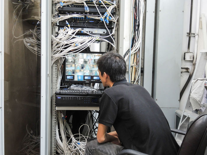 Rear view of man sitting in server room 
