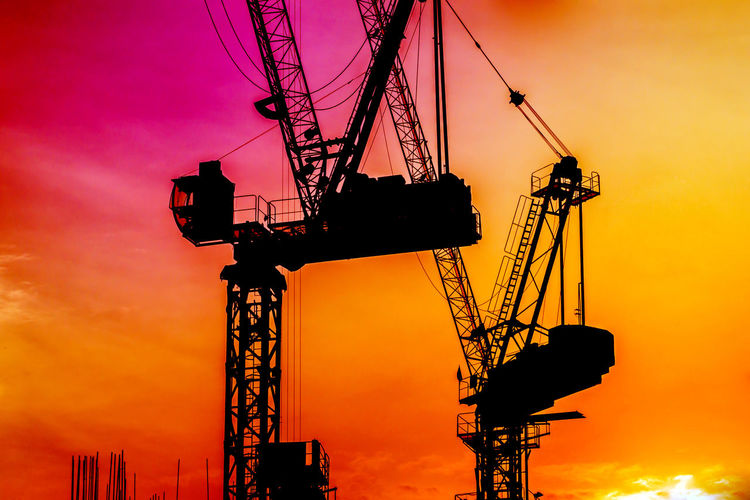 Low angle view of silhouette crane against sky during sunset