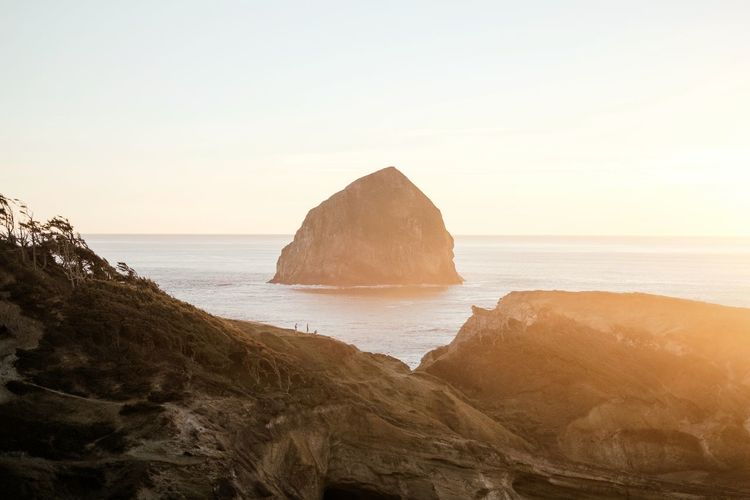Rock formation on beach against sky during sunset