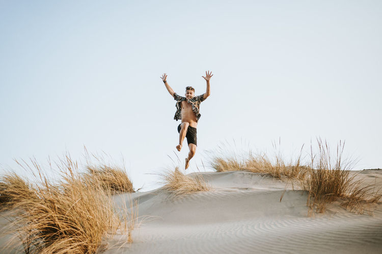 Cheerful young man jumping over sand at almeria, tabernas desert, spain
