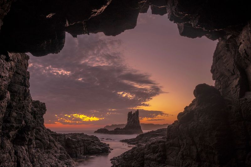 View of rocks at sea against sunset