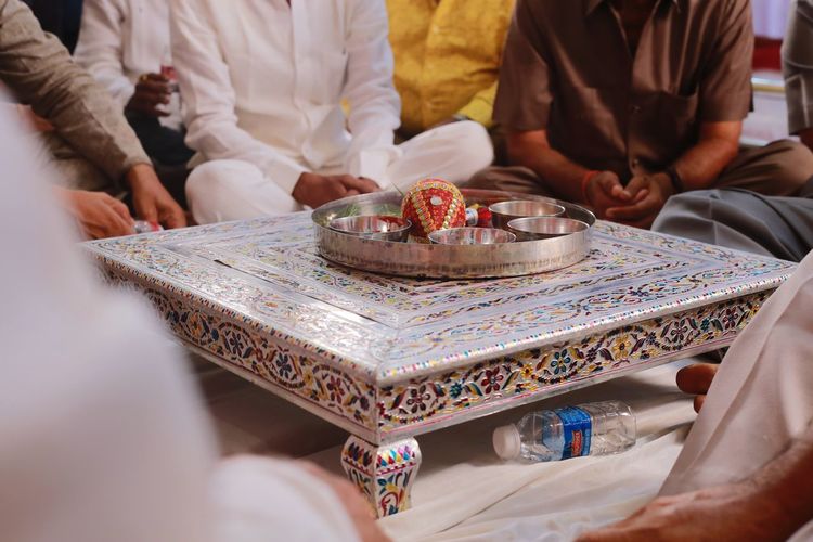Midsection of people sitting around religious offering in plate on table
