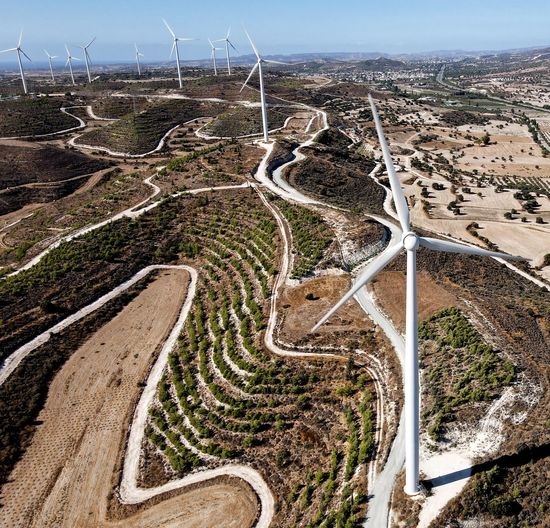 High angle view of road amidst land against sky, and windmills for electricity generation