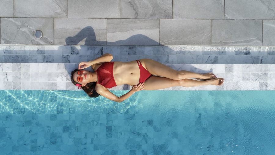 Full length of shirtless woman lying on swimming pool