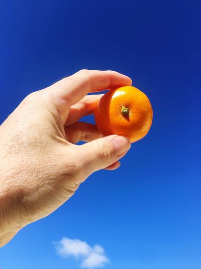 Holding up a mandarin against a blue sky