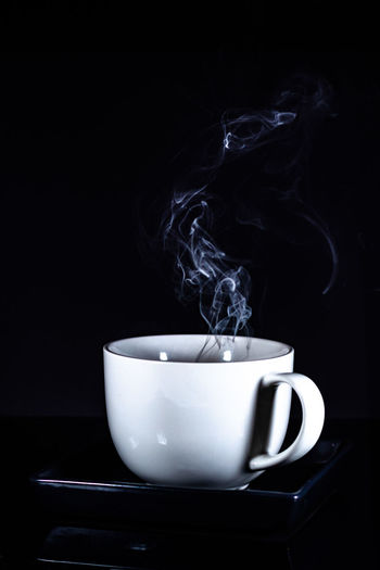 Close-up of coffee cup on table against black background