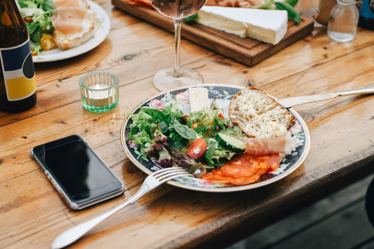 Close-up of healthy food served in plate by mobile phone on table during party