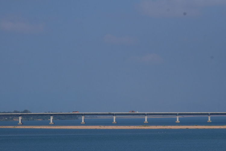 Bridge over sea against clear blue sky