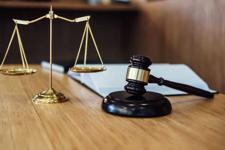 Close-up of gavel and weight scale on table in courtroom