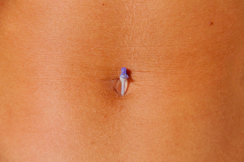 Midsection of woman with flower on abdomen