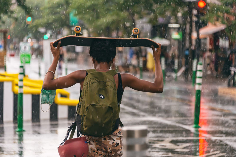 Rear view of man standing on wet street in rain