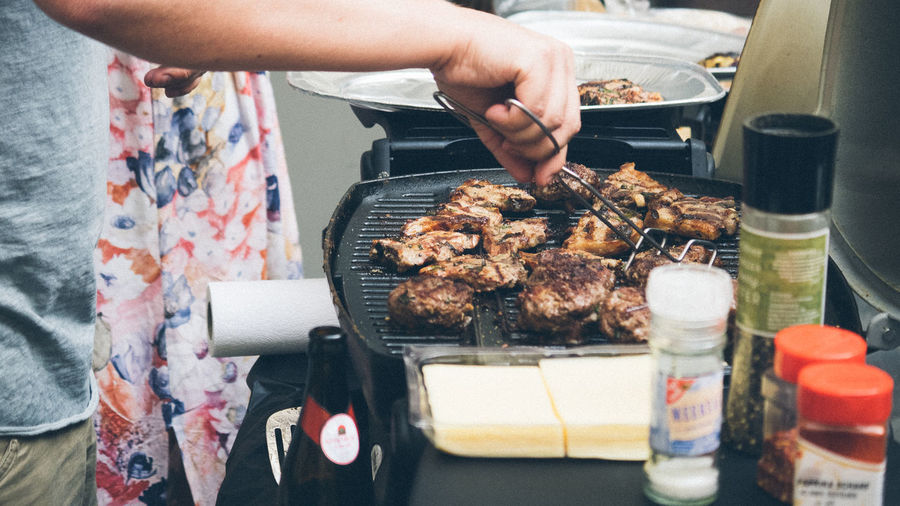 Close-up of man preparing food on barbecue grill