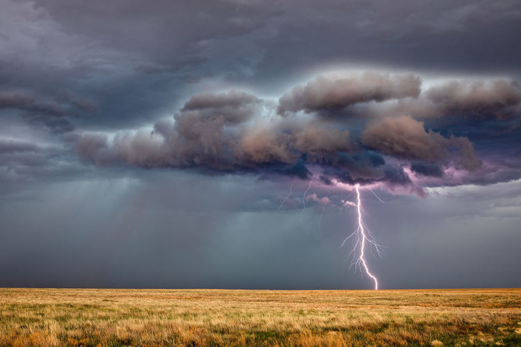 Panoramic view of lightning over landscape against cloudy sky