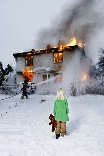 Girl watching firefighter spraying burning building