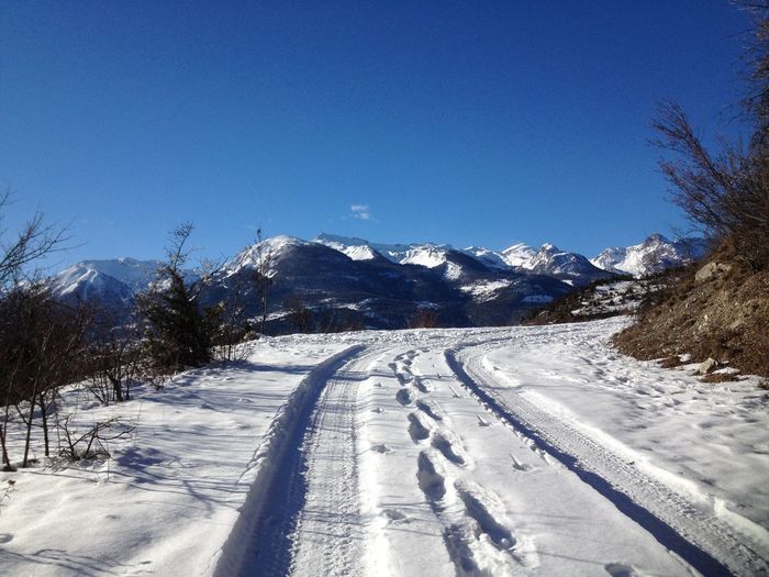 Snow covered landscape against clear blue sky