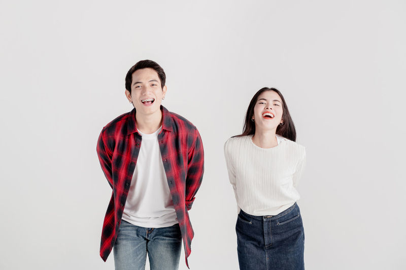 Portrait of young couple standing against white background