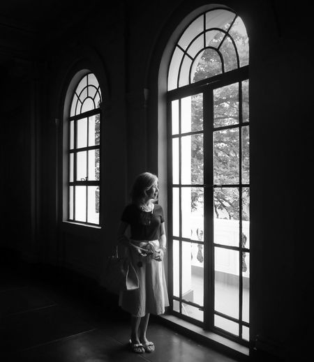 Rear view of woman looking through window