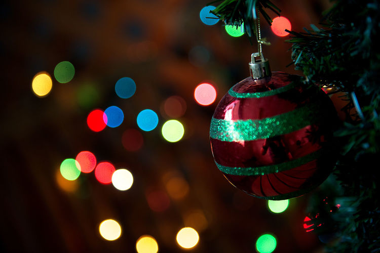 Defocused image of christmas bauble against illuminated christmas lights
